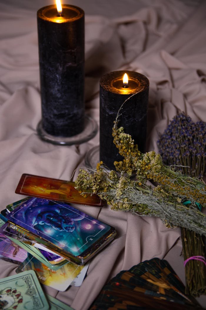 Intimate setting with tarot cards, candles, and herbs for mystical ambiance.