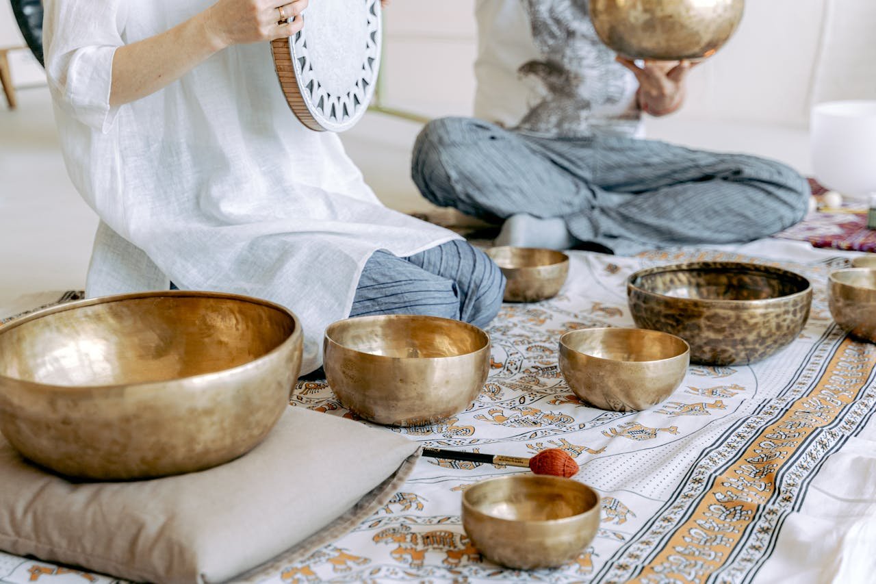Two individuals meditating with Tibetan singing bowls for mindfulness and relaxation.