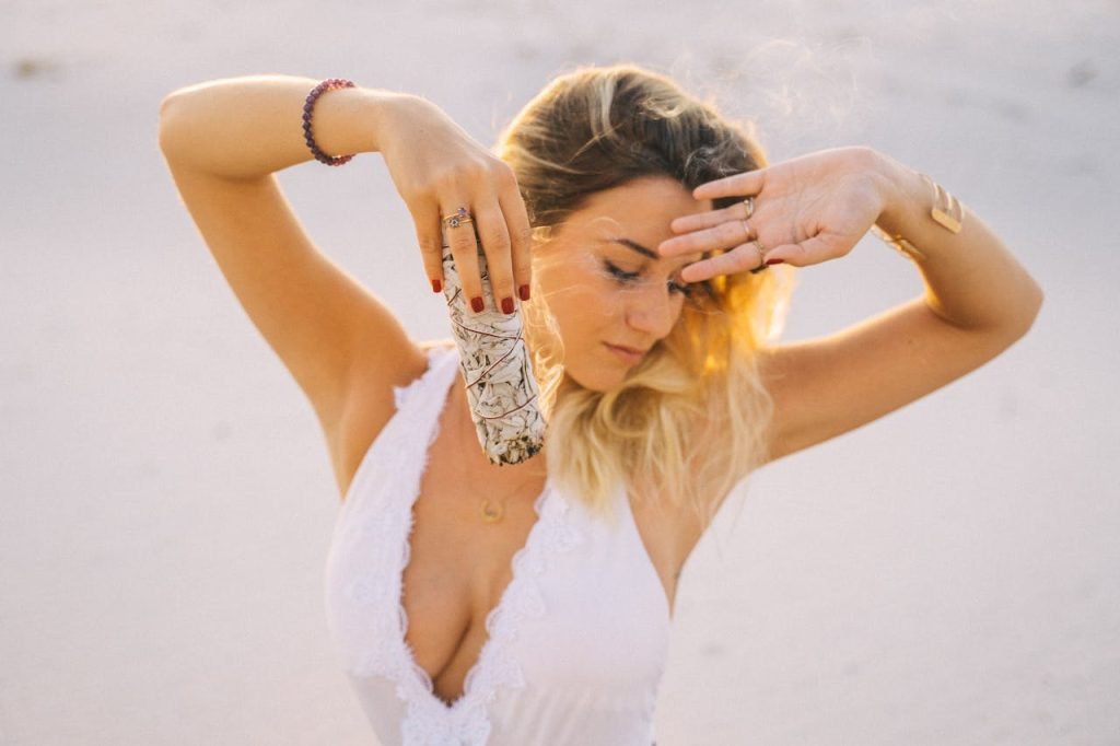 A serene woman practicing sage smudging outdoors for calming and purification.