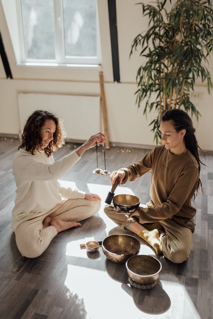 Two adults meditating indoors with Tibetan singing bowls, embracing tranquility and wellness.